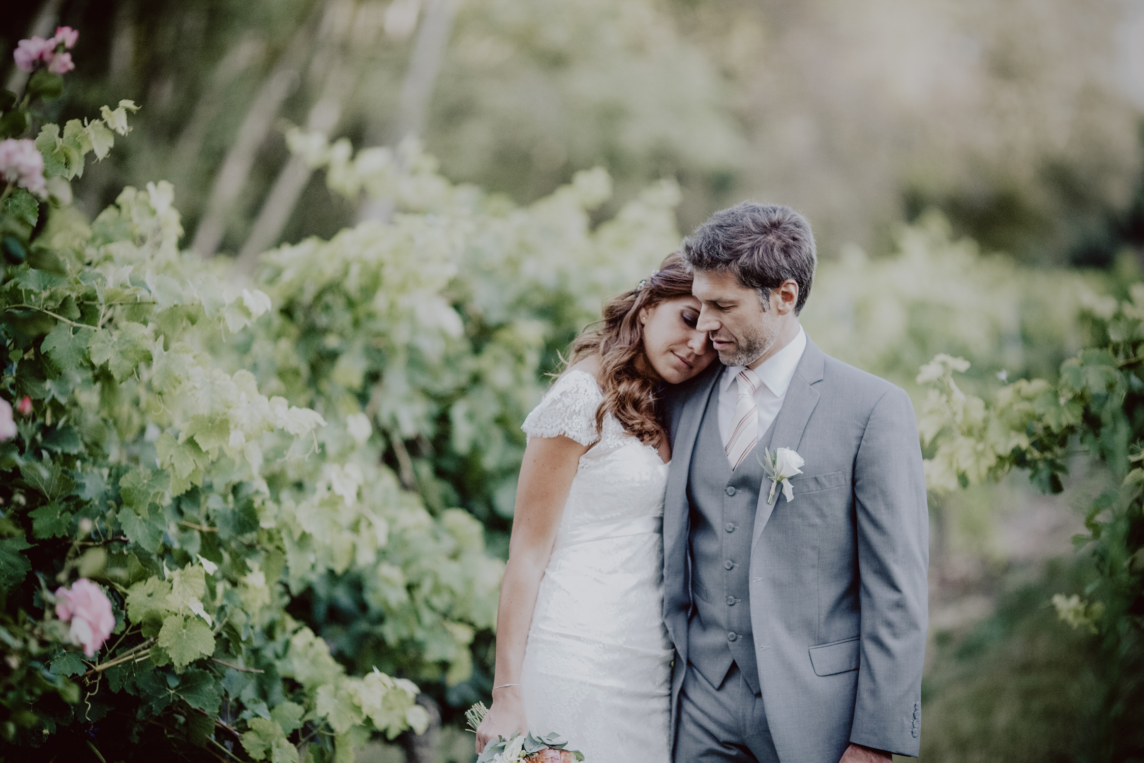 couple de mariés dans une allée de vignes et de roses